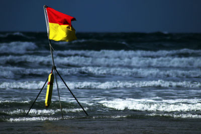 Yellow flag on beach against sky