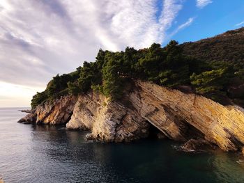 Rock formation by sea against sky