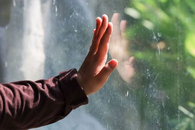 Midsection of person on wet glass during rainy season