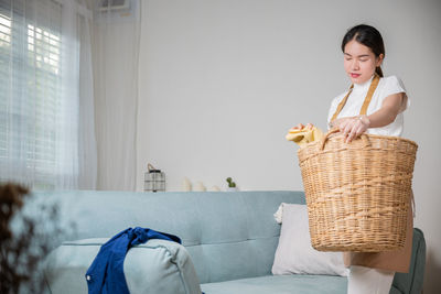 Side view of woman sitting on bed at home