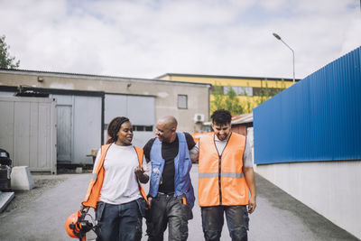 Female construction worker talking with male colleagues while walking on road