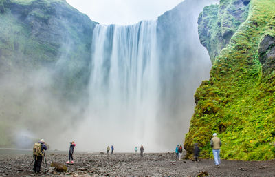 Panoramic view of people standing at waterfall