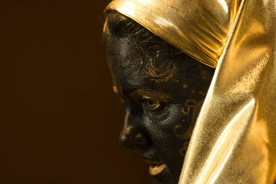 Portrait of a woman with black and gold make up, close up