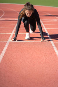 Full length of young woman getting ready for running on track