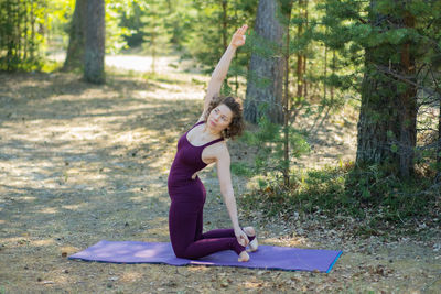 Full length of young woman exercising in forest