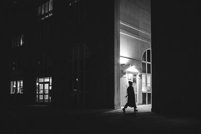 Rear view of woman walking in illuminated building at night