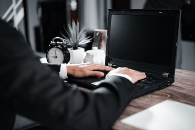 Midsection of man using laptop on table