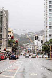 Cars on road in city against sky