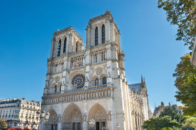 Notre dame de paris - people at famous cathedral with sun and blue sky before fire april 15, 2019