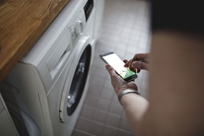 Cropped image of senior woman using mobile phone in bathroom at home