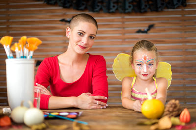 Portrait of smiling mother and daughter sitting at home