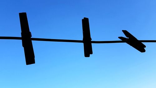 Low angle view of silhouette fence against clear blue sky