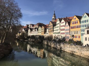 Buildings by river in city against sky