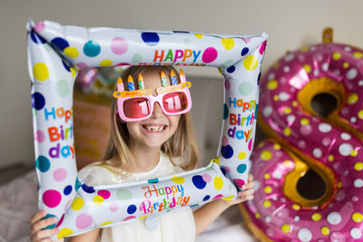 Smiling girl holding balloon at home