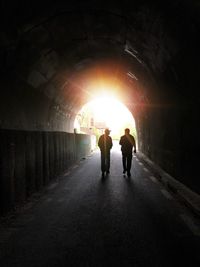 Rear view of silhouette man walking in tunnel