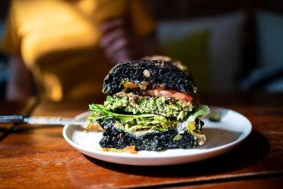 Cut half of broccoli quinoa charcoal burger topped with guacamole, mango salsa and fresh salad.