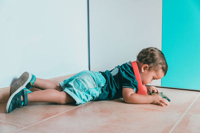 Boy lying on floor against wall at home
