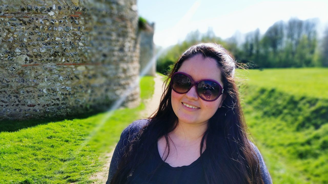 portrait, looking at camera, young adult, person, smiling, sunglasses, front view, young women, headshot, lifestyles, leisure activity, focus on foreground, happiness, toothy smile, casual clothing, close-up, grass