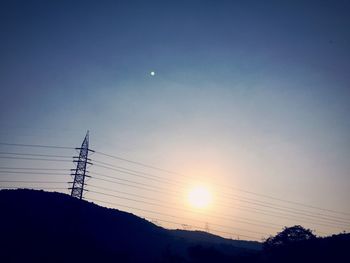 Low angle view of silhouette electricity pylon against sky during sunset