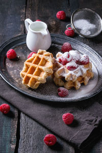 Close-up of waffles with raspberries in plate on table