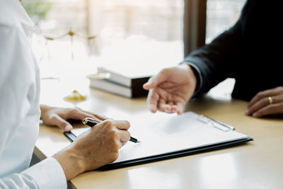 Midsection of couple holding hands on table