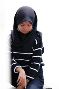 Full length of young woman sitting against white background