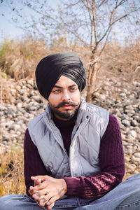 Portrait of young man sitting on field