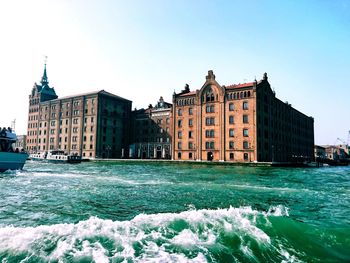 View of buildings by sea against clear sky