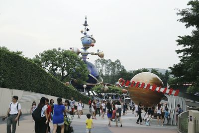 People walking on footpath in park against clear sky