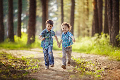 Full length of real brothers siblings running in forest