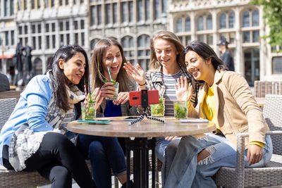 Portrait of smiling friends sitting on table