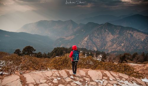 Rear view of woman standing on mountain against sky