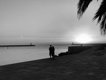 Silhouette people standing on beach against sky