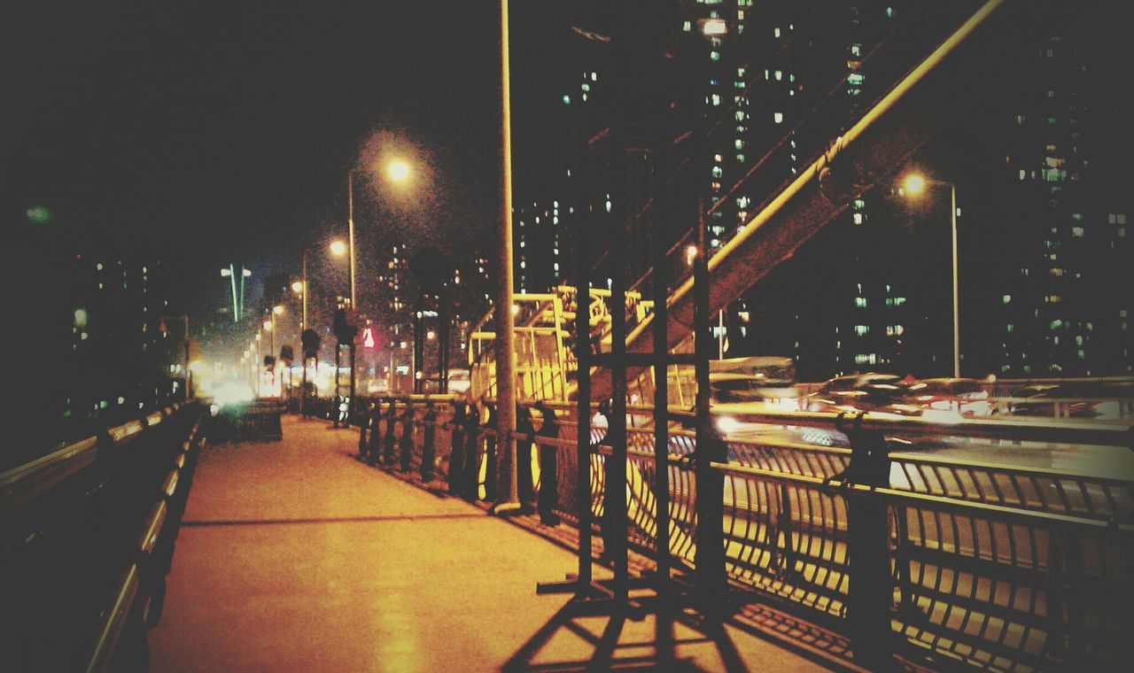 illuminated, night, street light, built structure, architecture, transportation, lighting equipment, city, building exterior, the way forward, railing, street, incidental people, mode of transport, city life, road, sky, diminishing perspective, bridge - man made structure, outdoors