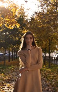 Portrait of woman standing against tree