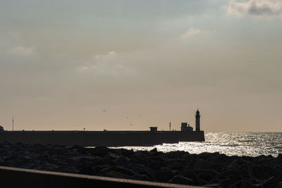 Lighthouse by sea against sky