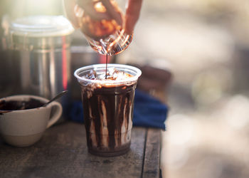 Close-up of hand holding drink on table