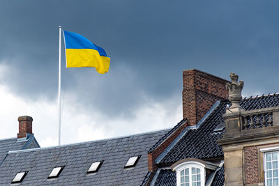 Ukrainian flag waiving on the roofs of the city with threatening grey clouds and dramatic sky