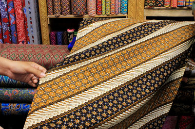 Cropped hand of person touching textile in store