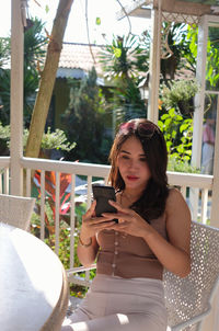 Young woman using mobile phone while sitting on table