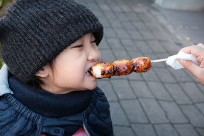 Cropped image of hand feeding dango dumpling to girl