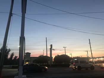 Cars on road against sky during sunset