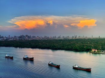 Boats on chao praya river bangkok against sunset sky