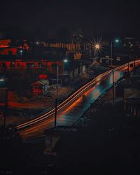 Illuminated railroad tracks in city at night