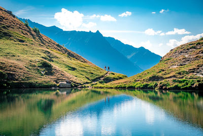 Mid distance of hikers on rocky mountain by lake