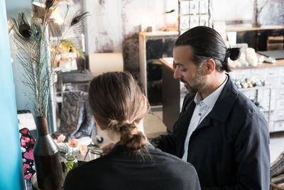 Rear view of female owner standing by mature male customer at store