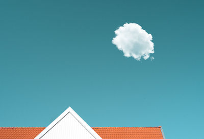 Low angle view of building against turquoise sky with single cloud. 