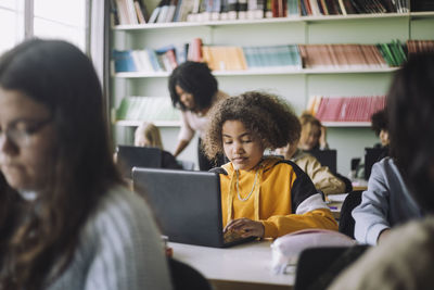 Girl using laptop at desk while studying in classroom