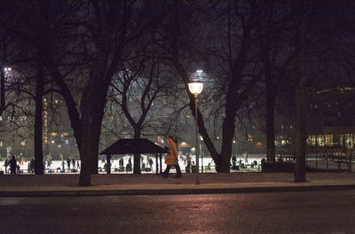 Rear view of man walking on footpath at night