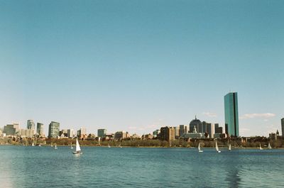 Sea by buildings against clear sky